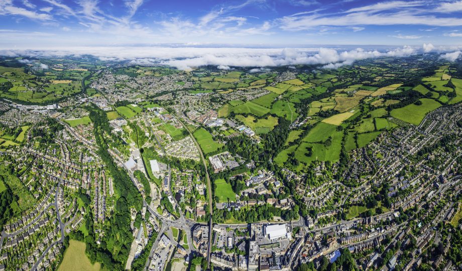 Aerial panorama over homes and gardens suburban streets green fields Aerial panorama over homes and gardens suburban streets green fields