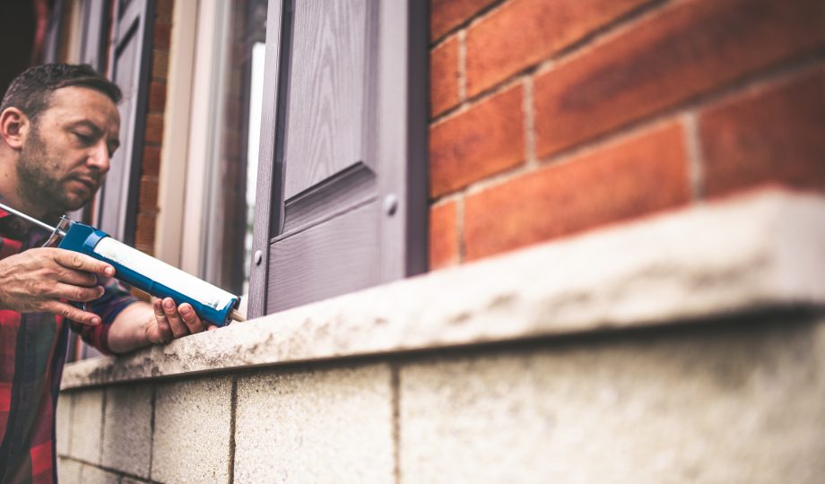 Man applying caulking around window frame Man applying caulking around window frame