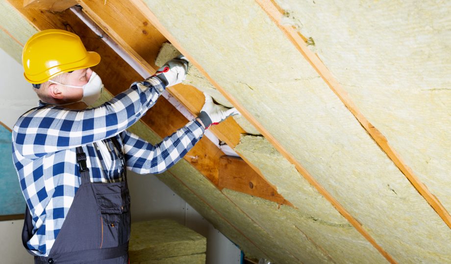Man installing thermal roof insulation layer – using mineral wool panels. Attic renovation and insulation concept Man installing thermal roof insulation layer – using mineral wool panels. Attic renovation and insulation concept